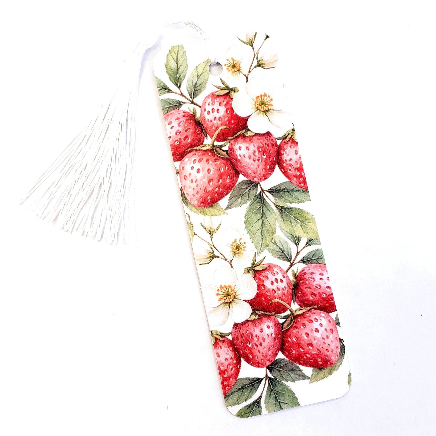 White bookmark with a tassel. The bookmark features a watercolor illustration of red strawberries and white flowers on green leaves.