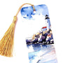 A watercolor bookmark featuring a lighthouse on a rocky shore with blue water and white foamy waves. The bookmark has a gold tassel.