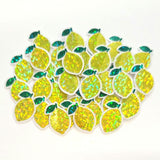 May include: A collection of yellow lemon-shaped sticker embellishments with green leaves. The lemons are sparkly with green leaf and clear borders.