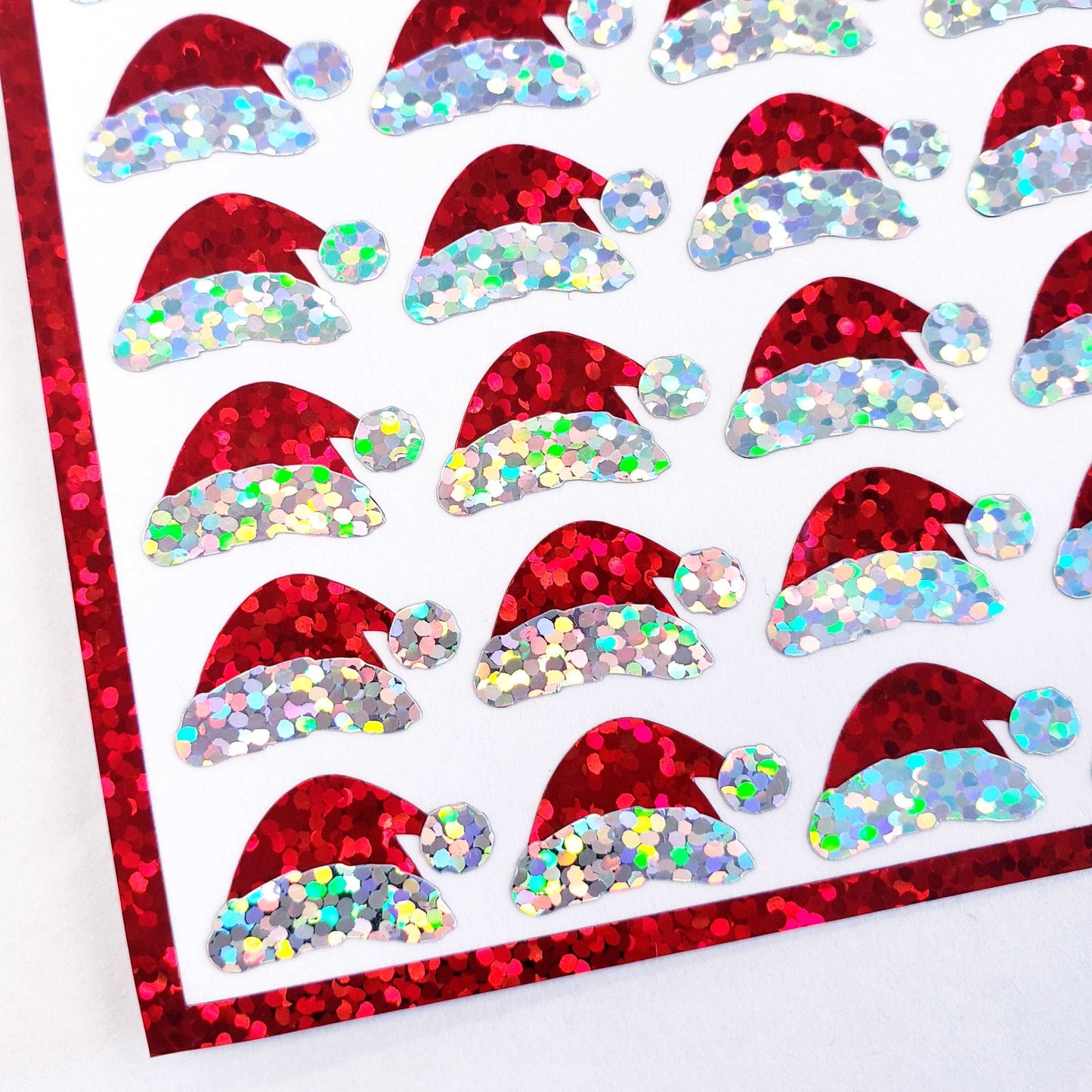 Mini Red Santa Claus Hats Sticker Sheet. Set of 78 Santa Hat decorative glitter stickers for ornaments, crafts, envelopes and gift bags