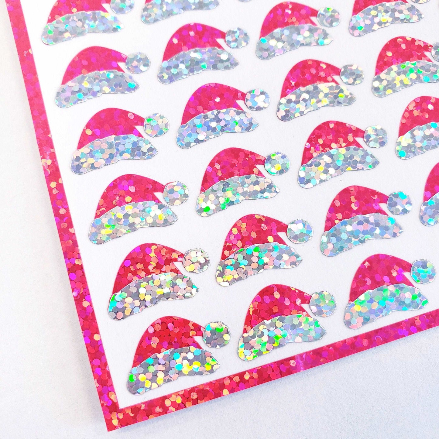 Mini Pink Santa Claus Hats Sticker Sheet. Set of 78 Santa Hat decorative glitter stickers for ornaments, crafts, envelopes and gift bags