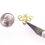 A gold bee sticker with a textured surface. The bee is being held by a craft knife.