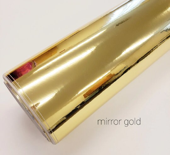 A roll of gold mirror vinyl. The vinyl is shiny and reflective, with a metallic finish. The text "mirror gold" is printed on the bottom of the image.