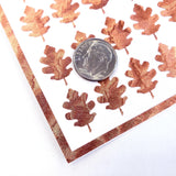 copper oak leaf stickers. A US dime is placed on the card for scale.