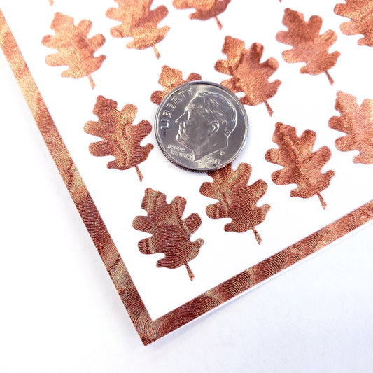 copper oak leaf stickers. A US dime is placed on the card for scale.