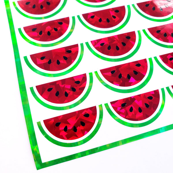 A sheet of holographic watermelon stickers. The stickers are red with black seeds and green outlines.