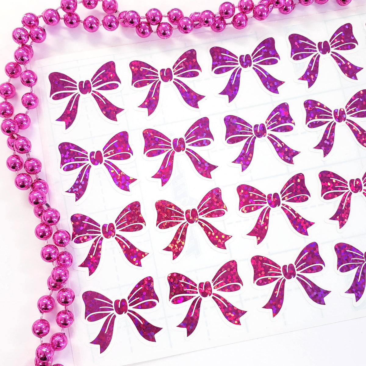 Hot Pink Sparkly Bow Sticker Sheet. Set of 20 individual peel and stick small pink bow shaped stickers with white outline.