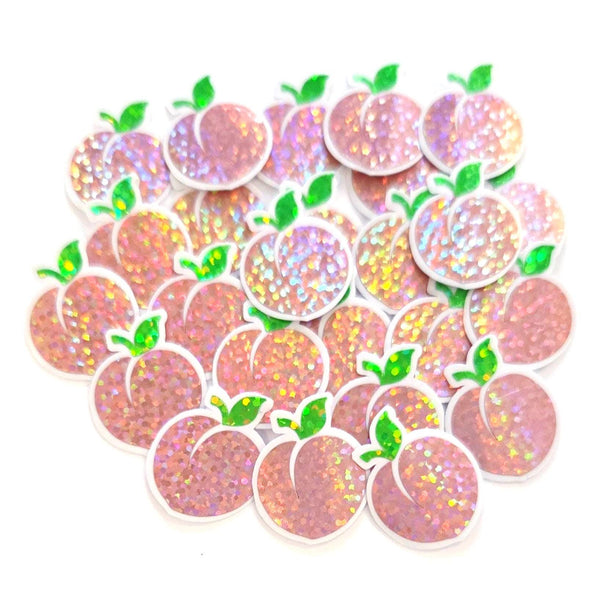 May include: A collection of peach-shaped sticker embellishments with a glittery, iridescent finish. Each peach has a green leaf and a clear border. The peaches are a mix of pink and orange hues, creating a shimmering effect.