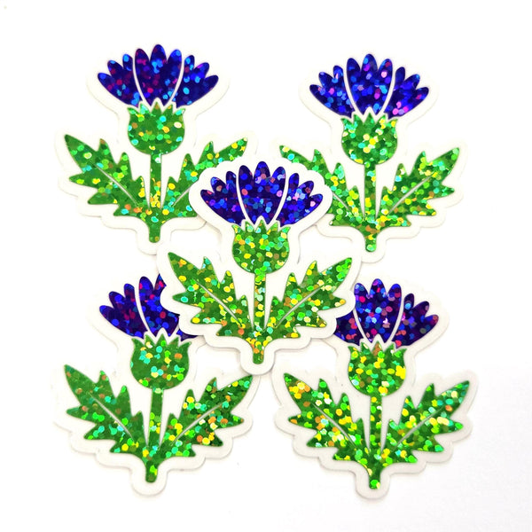 Five stickers featuring a stylized thistle sticker. The flowers are a deep purple with glitter accents, and the leaves are green.