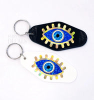 
              Retro Motel Style Keychain, white plastic key holder with sparkly blue and gold evil eye graphics, gift under 10 dollars
            